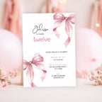 12th birthday Invitation card with pink ribbons and floral decorations on a blurred background