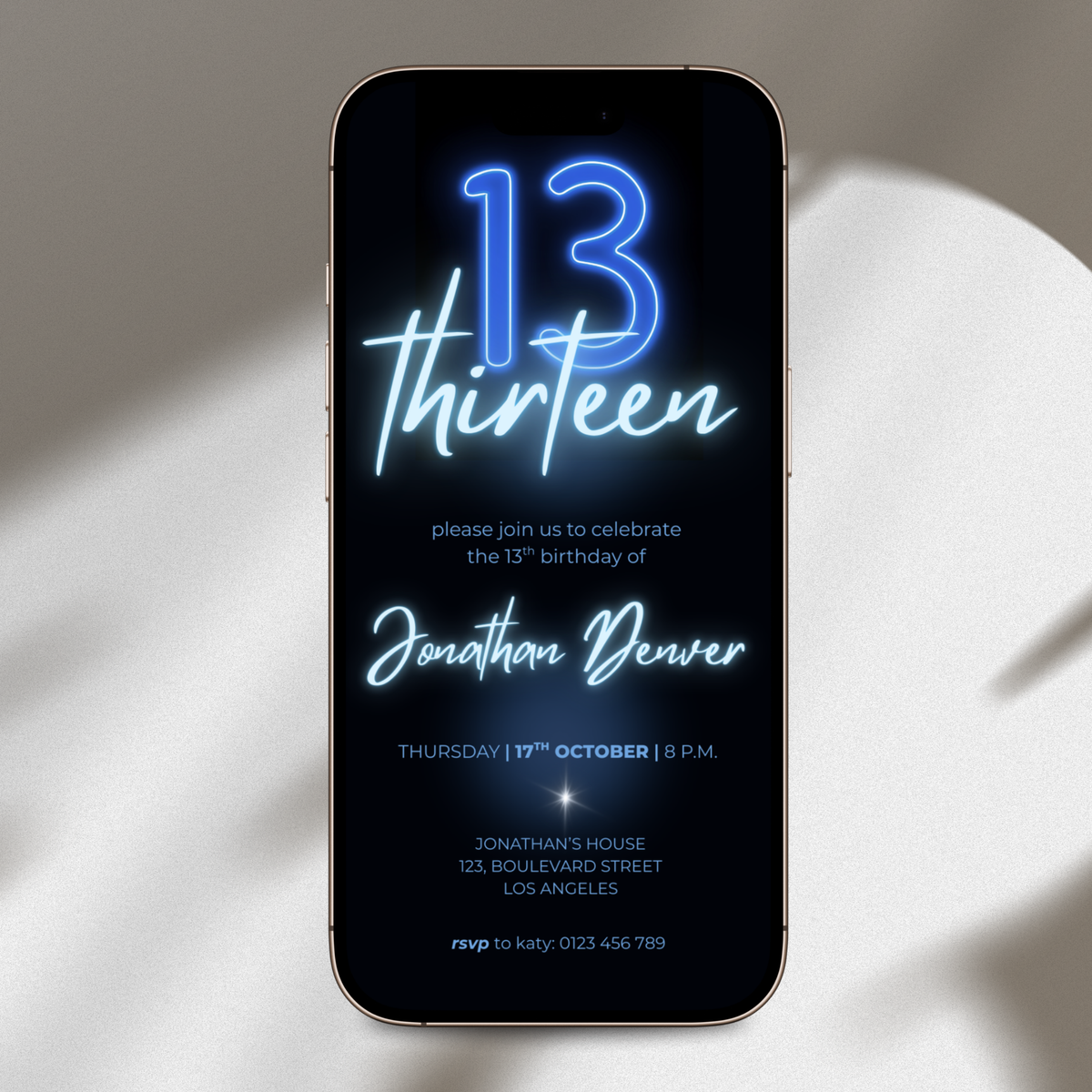 A smartphone with a black screen displaying a neon-style 13th birthday invitation for Jonathan Denver, photographed on a softly lit beige surface with shadows.