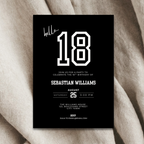 Black birthday invitation card with white text on a beige fabric background