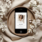 Phone with a 30th birthday invitation on a wooden plate surrounded by white flowers