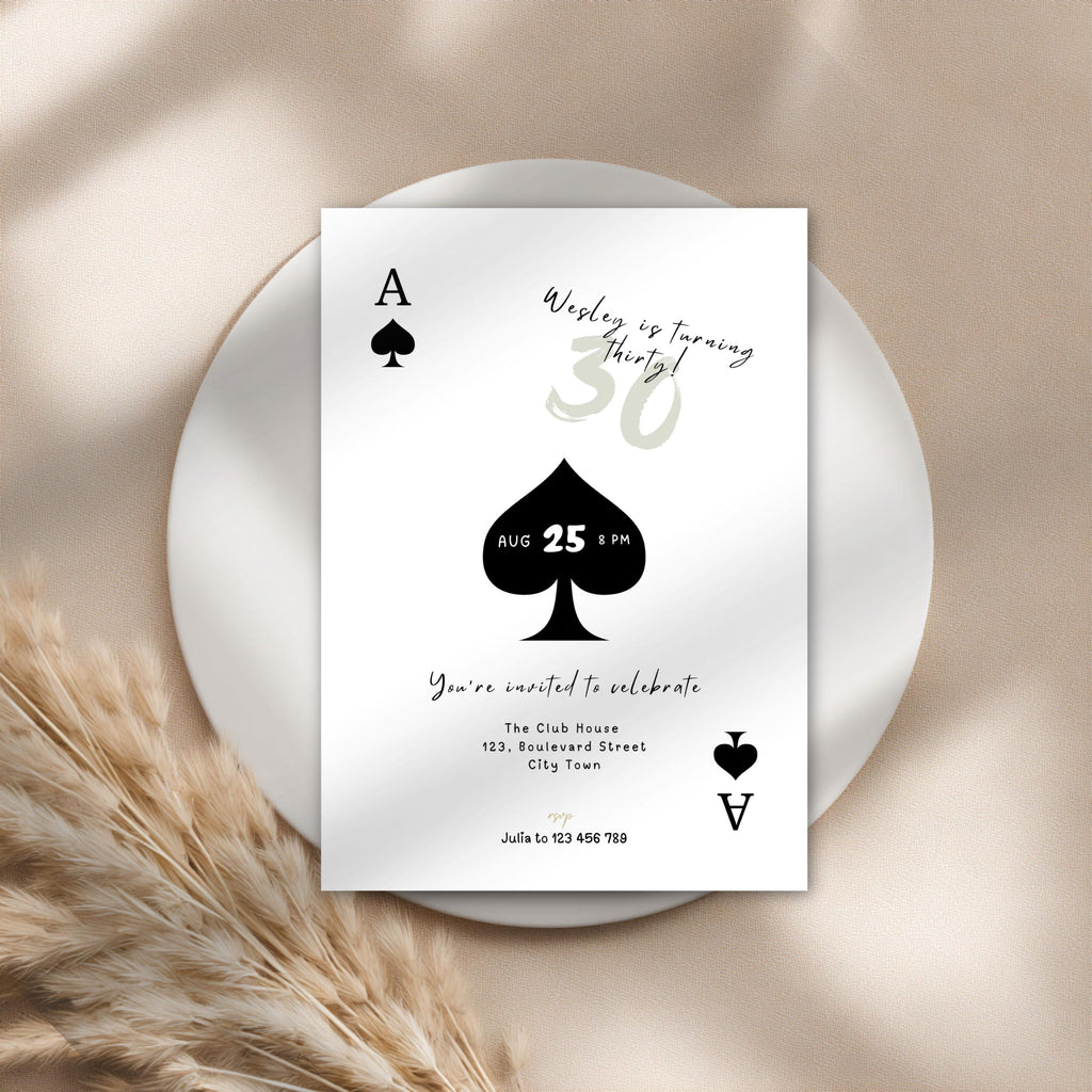 Playing card design birthday invitation on a white plate with pampas grass