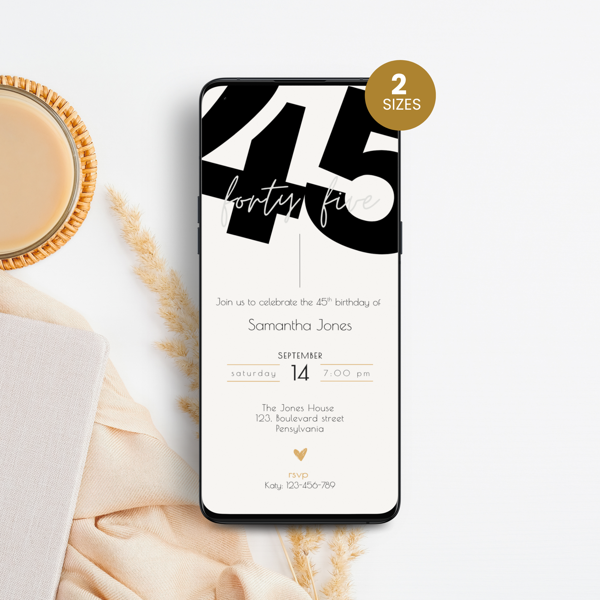 Phone displaying a 45th birthday invitation with a cup of coffee and decorative elements on a white surface.