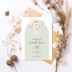 Invitation card with floral design and envelope on a white background with dried plants.