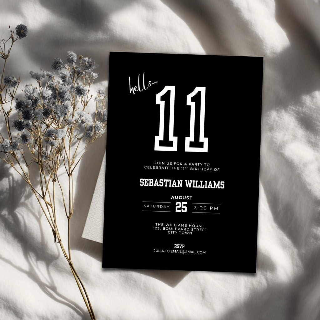 Black 11th birthday invitation card with white text on a light fabric background