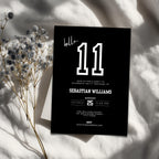 Black 11th birthday invitation card with white text on a light fabric background