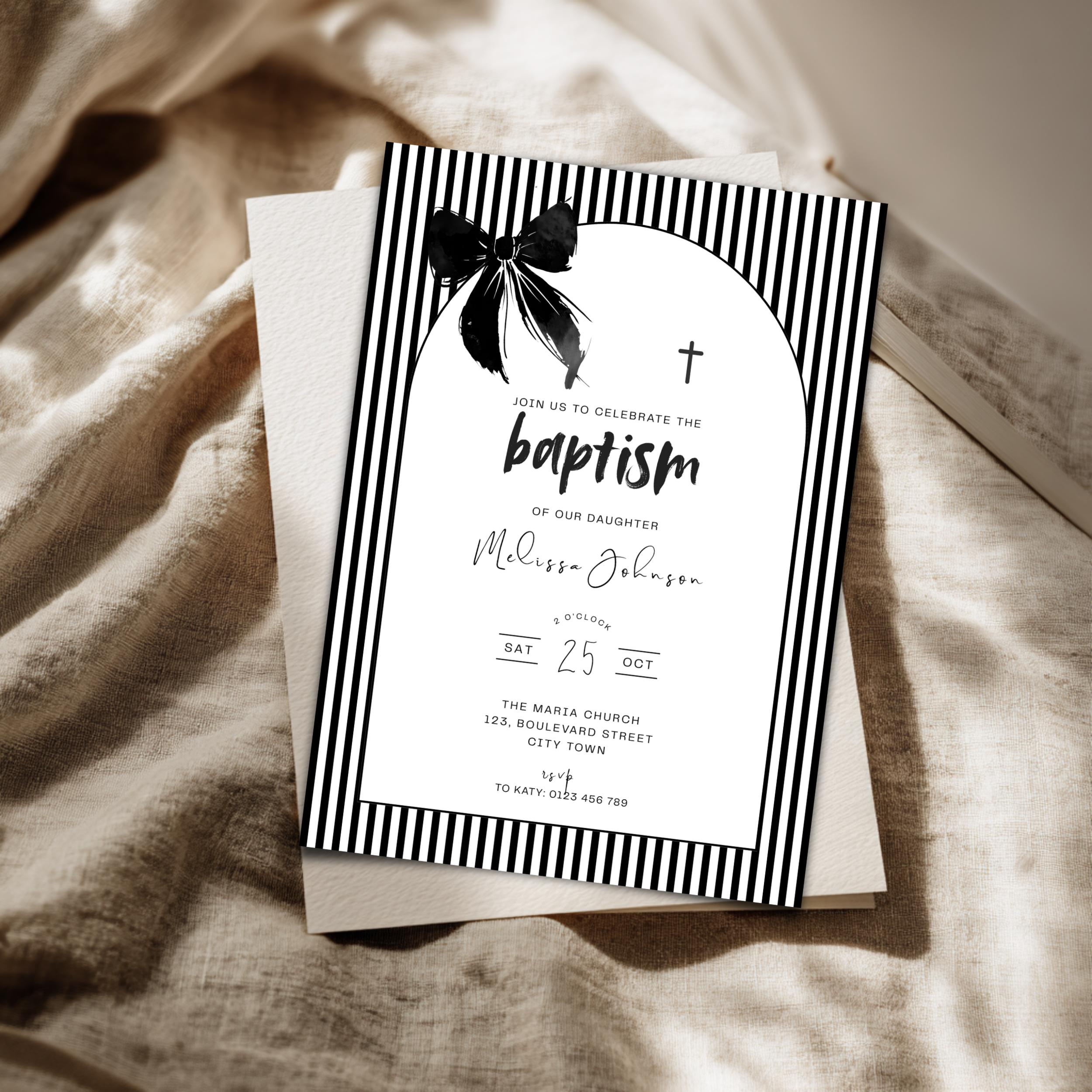 Baptism invitation card with black and white design on a textured fabric background