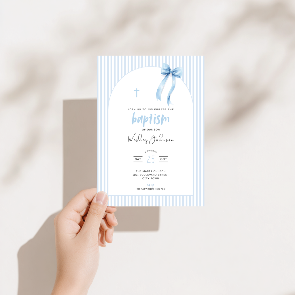 Hand holding a baptism invitation card with a blue ribbon on a neutral background