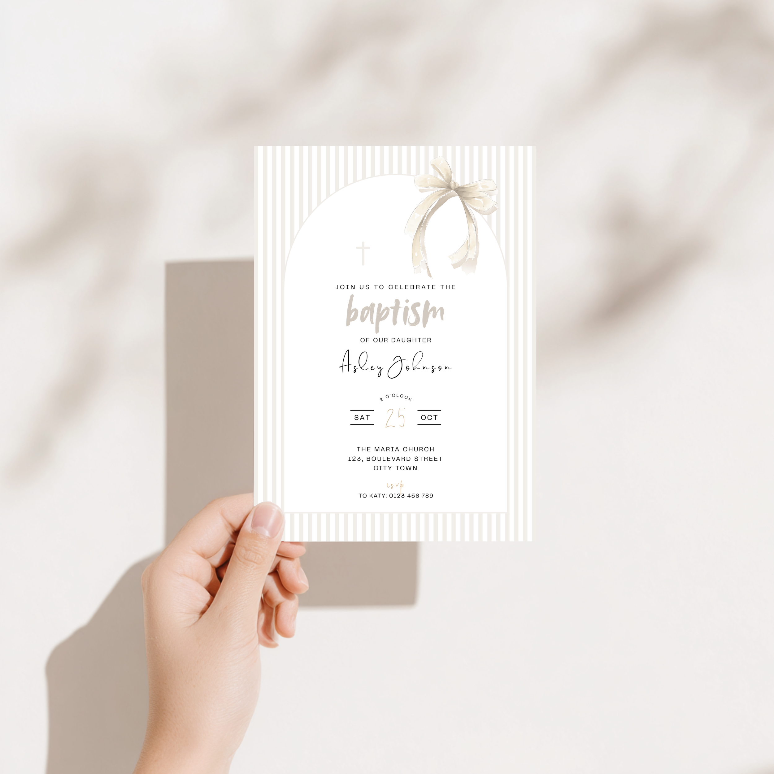 Hand holding a baptism invitation card with a decorative design on a soft background