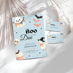 Halloween blue little boo baby shower invitation suite with a light blue card, matching RSVP card, and entrance card, decorated with cute cartoon ghosts, skulls, bats, and a witch, styled on a white surface with decorative dried palm leaves.