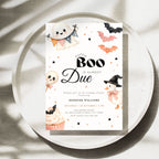 A Halloween baby shower invitation card styled on a round white tray with soft leaf shadows. The invitation features cute watercolor illustrations of a ghost, bats, a pumpkin, a cupcake, and a witch hat around the text 'A Little Boo Is Almost Due'.