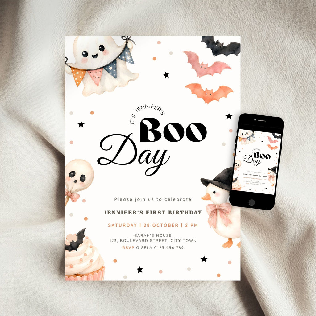 A Halloween-themed first birthday invitation card is styled on a soft beige fabric background next to a smartphone showing the matching digital design. The card features cute watercolor illustrations of a ghost, bat, skull, cupcake, and a witch, with the text 'It's Jennifer's Boo Day'.
