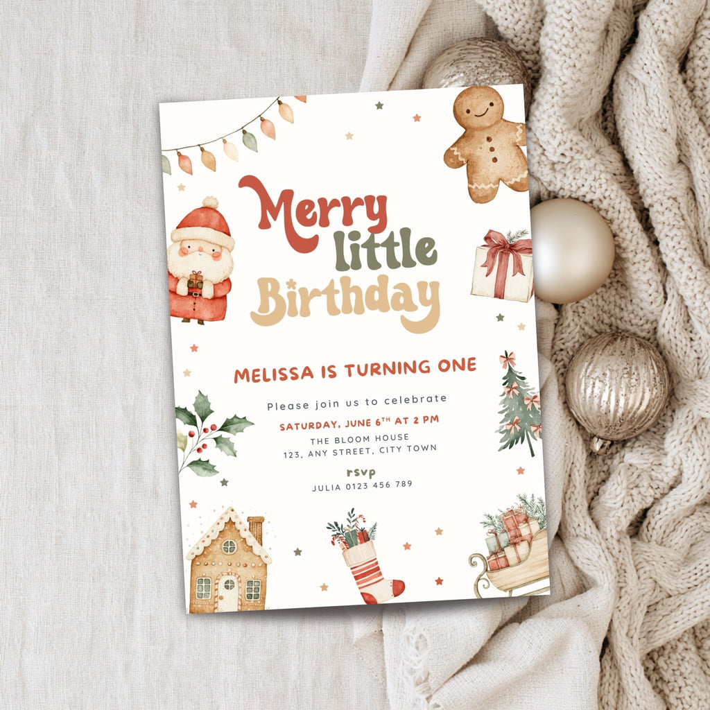 A Christmas-themed birthday invitation card styled on a light fabric background with a beige knit sweater and gold ornaments. The card features watercolor illustrations of a Santa Claus, a gingerbread man, a house, a stocking, and a sleigh, with the text 'Merry little Birthday' and event details.