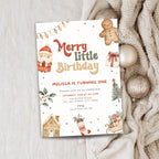 A Christmas-themed birthday invitation card styled on a light fabric background with a beige knit sweater and gold ornaments. The card features watercolor illustrations of a Santa Claus, a gingerbread man, a house, a stocking, and a sleigh, with the text 'Merry little Birthday' and event details.