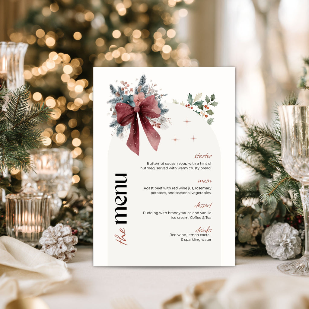 A vertical christmas dinner menu card with a white background, featuring a watercolor winter holiday design with a burgundy bow, green holly leaves, and gold star accents. The menu lists courses and items like butternut squash soup and roast beef.