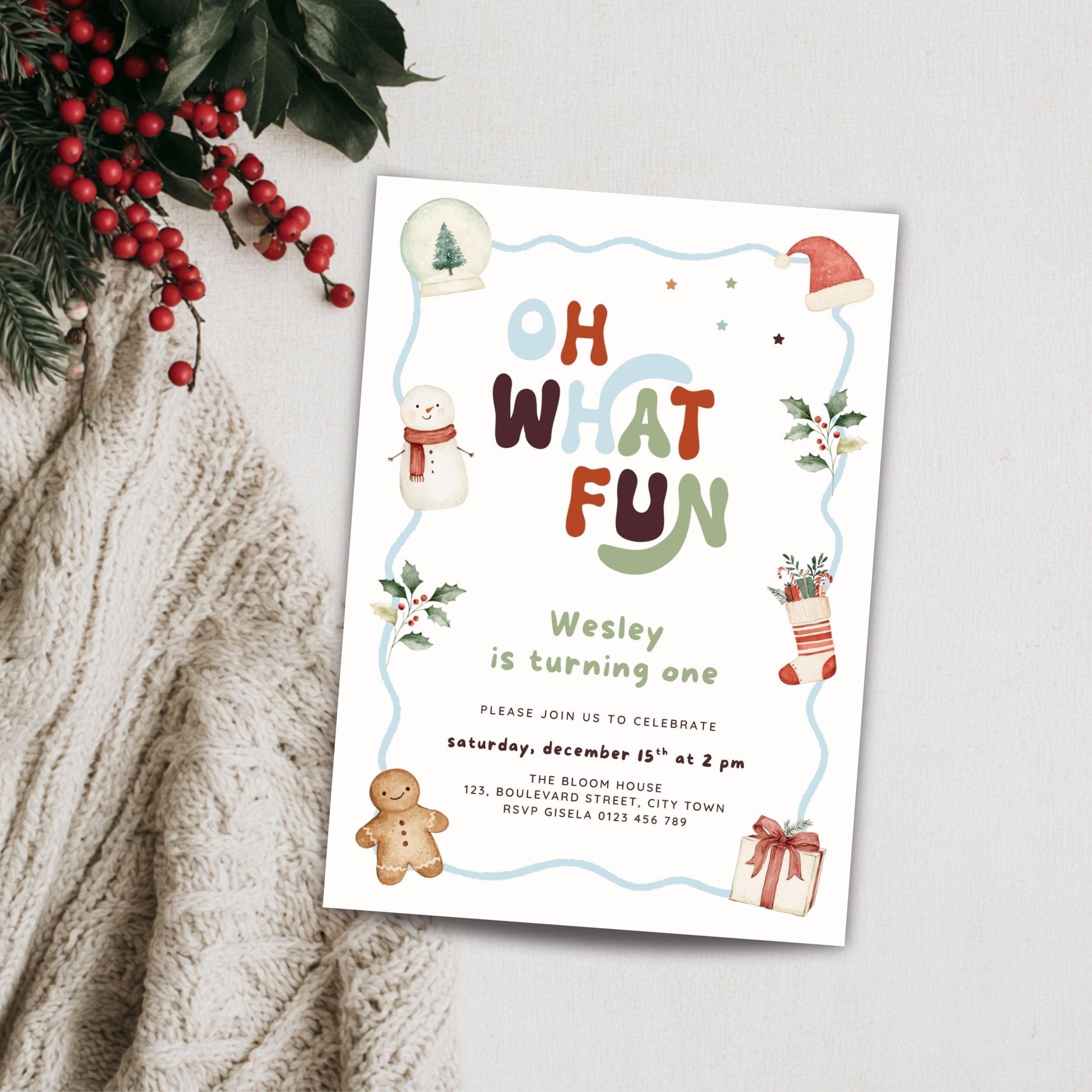 A festive Christmas-themed birthday invitation card styled on a light gray textured surface with a knitted cream sweater and red berries in the corner. The card features colorful text reading 'Oh What Fun' with illustrations of a snowman, gingerbread man, Santa hat, stocking, and gift.