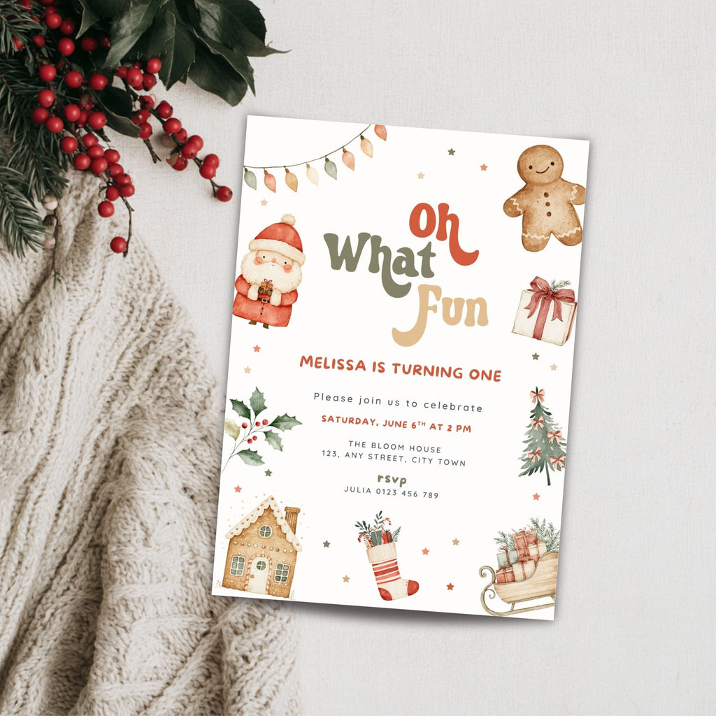 A Christmas-themed birthday invitation card styled on a light gray surface with a knitted cream sweater and red berries in the corner. The card features festive illustrations including a gingerbread man, Santa, a Christmas tree, a stocking, and the text 'Oh What Fun' and a birthday celebration invitation.