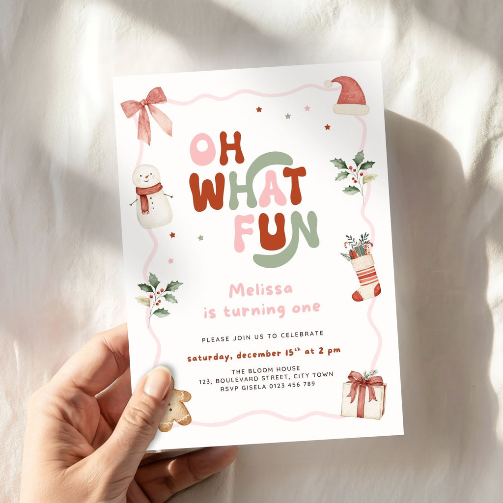 Christmas first birthday invitation for a girl featuring Oh What Fun lettering, watercolor snowman, gingerbread cookie, Santa hat, holly leaves, Christmas stocking, presents, pink bow, and festive holiday details. Digital download.