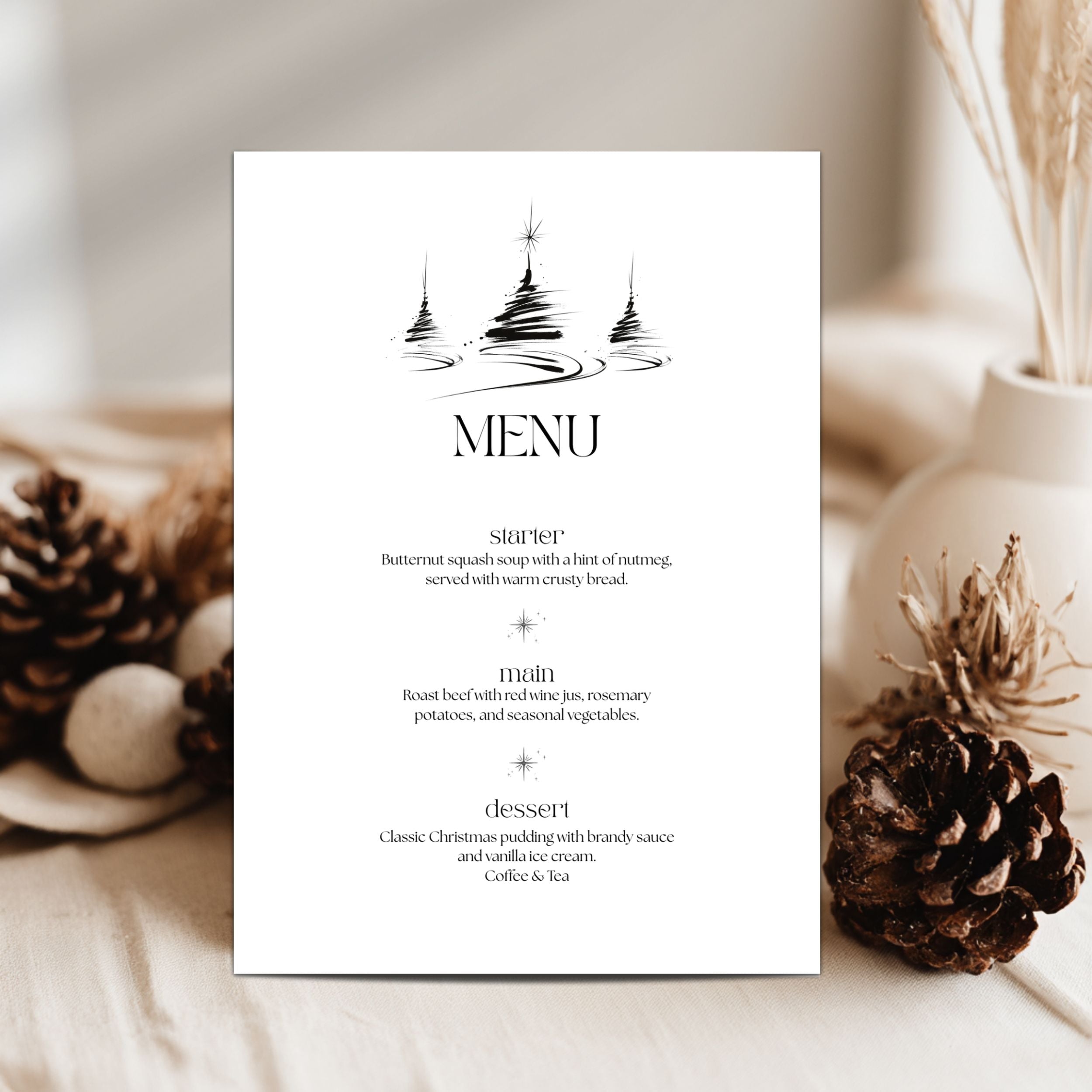 A vertical white paper menu card with black printed text and a simple black tree illustration at the top, styled on a light fabric surface with pinecones and dried botanicals in the background.