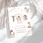A children's dino 2nd birthday invitation card styled in a flat-lay with dried palm leaves. The card is white with pastel pink and beige dinosaur illustrations and the text 'Our Dino is a Two Rex' with two circular photo cutouts in the center.