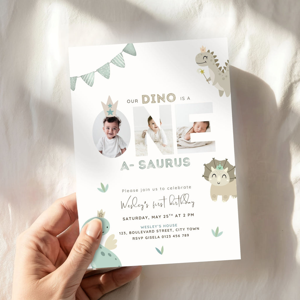 A hand holds a customizable dinosaur-themed first birthday invitation card against a soft, white draped fabric background with warm sunlight shadows.