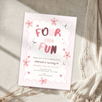A pink and white striped 'Four Ever Fun' birthday invitation card styled on a textured beige surface with a cream knit blanket and dried grasses.