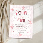 A pastel pink and white striped 'Four Ever Fun' 4th birthday invitation card styled on a beige fabric surface next to a cream-colored throw blanket.