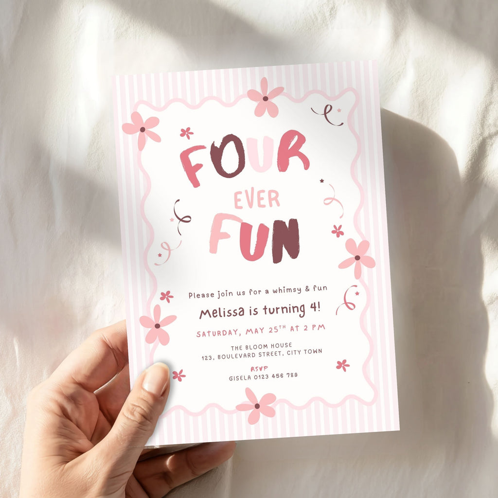 A hand holding a pink and white striped 'Four Ever Fun' 4th birthday invitation card with floral designs, set against a softly lit, textured white fabric background.