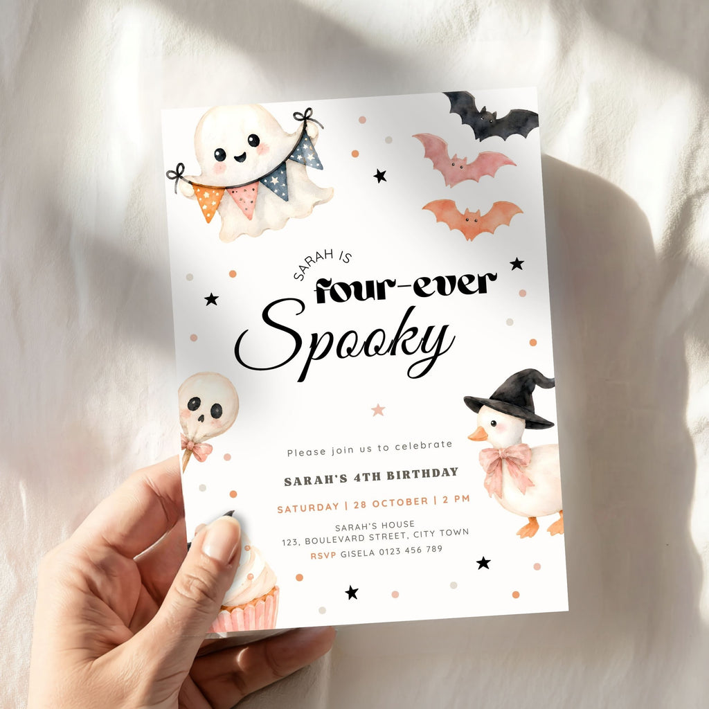 A hand holding a Halloween-themed birthday invitation card. The card features cute illustrations of a ghost, a pumpkin, a witch chick, and bats on a white background with black text reading 'Sarah is four-ever Spooky'.
