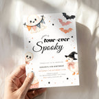 A hand holding a Halloween-themed birthday invitation card. The card features cute illustrations of a ghost, a pumpkin, a witch chick, and bats on a white background with black text reading 'Sarah is four-ever Spooky'.