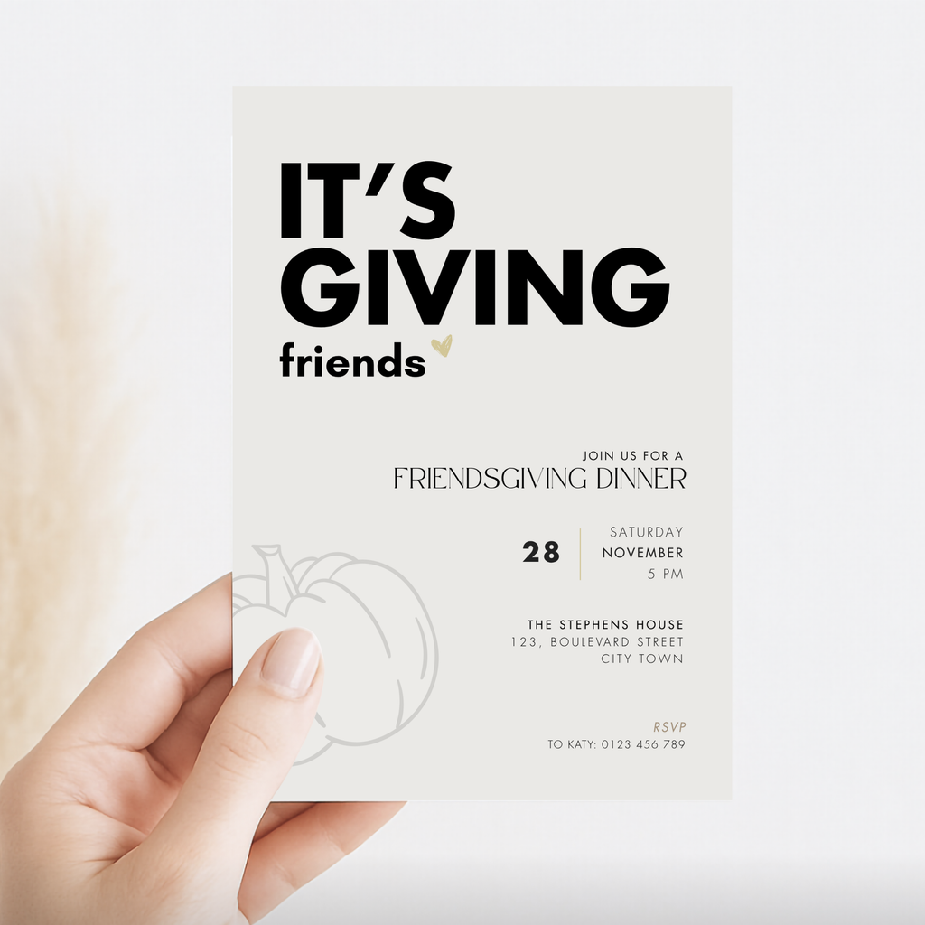 Hand holding a square Friendsgiving invitation card with bold text It's Giving friends and a pumpkin