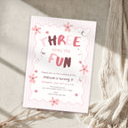 A pink and white striped three-year birthday invitation card styled on a textured beige surface with a cream knit blanket and dried grasses.