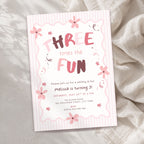 A pink and white striped 3rd birthday invitation card with floral illustrations and the text 'THREE times the FUN' in stylized lettering, photographed on a soft beige fabric background.