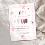 A pink and white striped birthday invitation card with floral illustrations and the text 'LET'S HAVE SOME FUN' and 'Melissa is turning 8!', photographed on a soft beige fabric background.