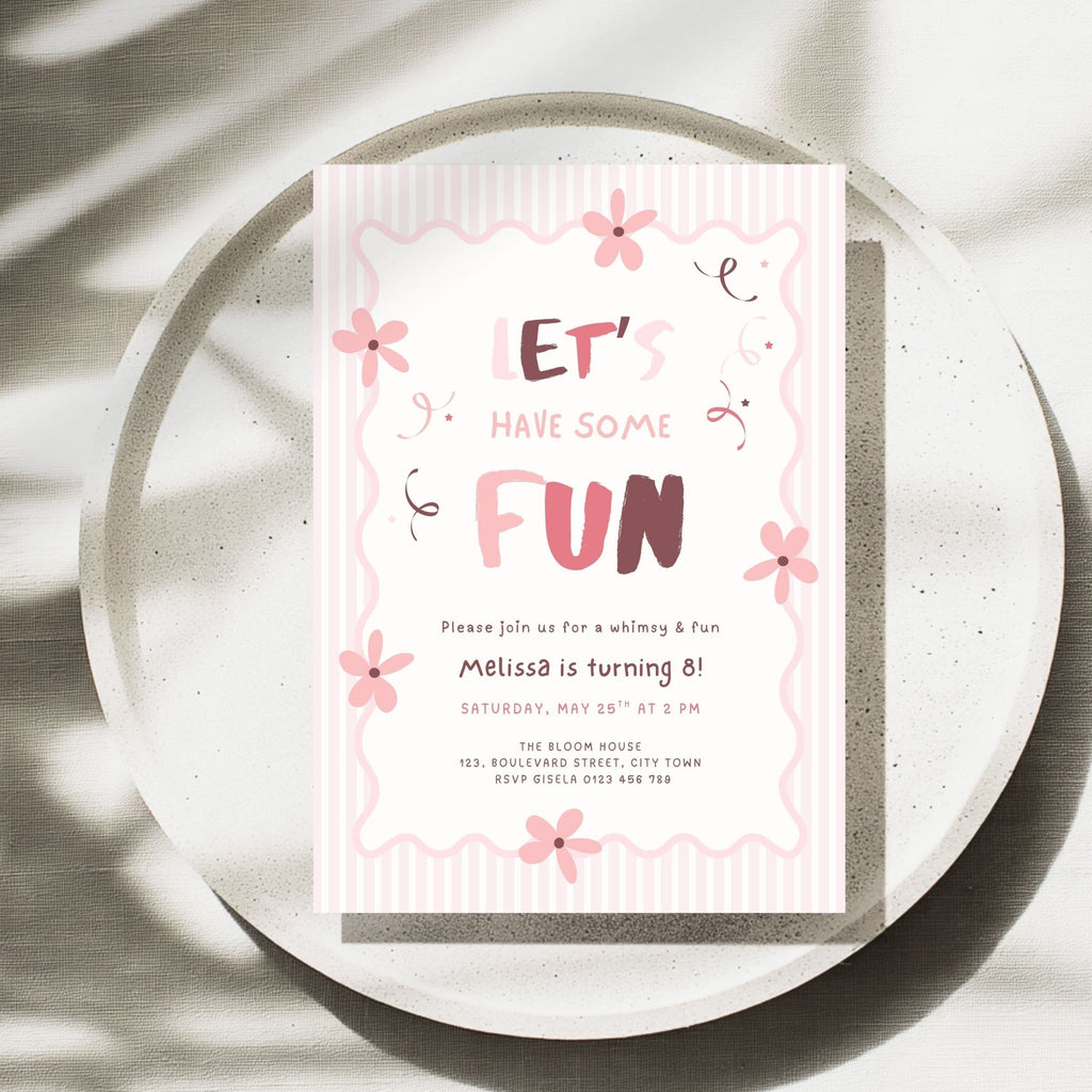 A pink and white birthday invitation card with cute floral doodles and the text 'LET'S HAVE SOME FUN' and 'Melissa is turning 8!', styled on a round speckled tray with soft leaf shadows.