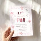 A hand holds a pink and white birthday invitation card that reads 'LET'S HAVE SOME FUN' with floral illustrations, set against a softly lit white fabric background.