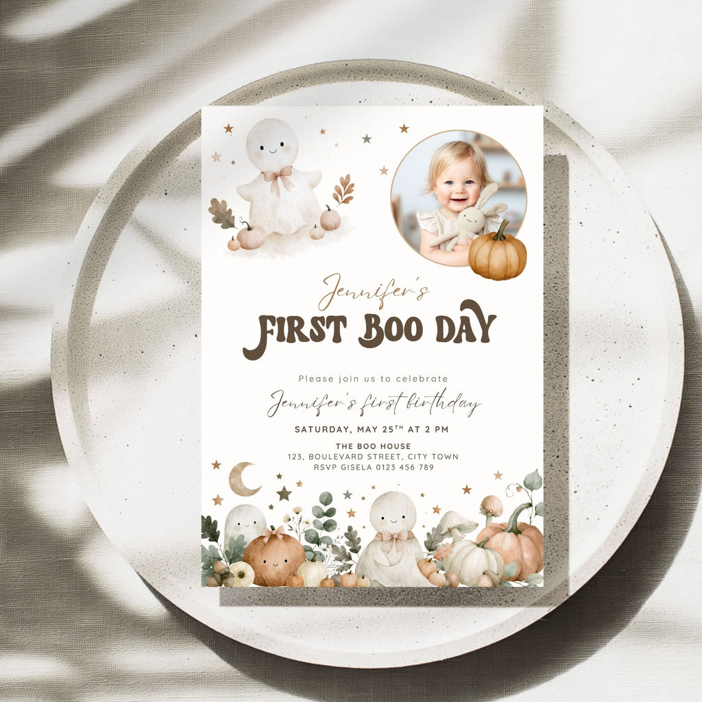 A square first birthday invitation card for 'Jennifer's First Boo Day' styled on a speckled white plate with soft shadows. The card features cute watercolor illustrations of white ghosts, pumpkins, stars, and a baby photo in the top right.