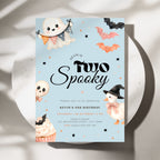 A square Halloween-themed birthday invitation card with a light blue background, featuring cartoon ghosts, bats, a skull, a turkey, and a cupcake. The card reads 'KEVIN IS Two Spooky' and includes birthday event details.
