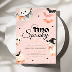 A pastel pink Halloween-themed birthday invitation card with cute illustrations of a ghost, bats, a skull, a snowman, and a cupcake, styled on a white plate with soft shadows.