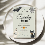 A square Halloween-themed birthday invitation card for 'Wesley's Spooky One' with cute illustrations of a bat, spider, spiderweb, snowman, and black cat, styled on a round ceramic plate with leaf shadows.