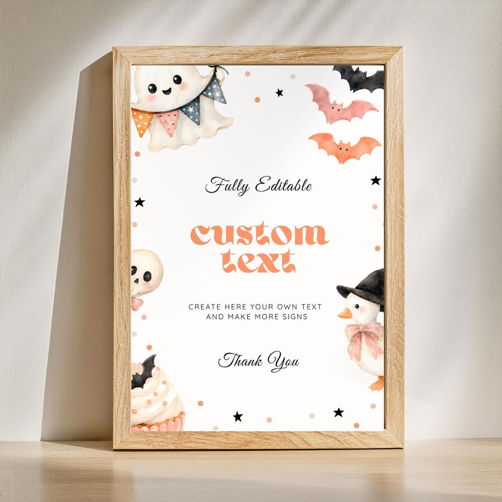 A framed Halloween-themed custom sign mockup leaning against a wall on a light wooden surface. The sign has a white background with cute illustrations of a ghost, bats, a skull, a penguin, and cupcakes, along with placeholder text reading 'Fully Editable custom text' and 'Thank You'.