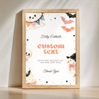 A framed Halloween-themed custom sign mockup leaning against a wall on a light wooden surface. The sign has a white background with cute illustrations of a ghost, bats, a skull, a penguin, and cupcakes, along with placeholder text reading 'Fully Editable custom text' and 'Thank You'.