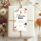 A wrapped gift box tied with twine and topped with a decorative 'Thanks Boo' thank-you tag, surrounded by dried flowers and autumn decor on a light neutral background.