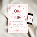 A pink and white striped 'One Happy Girl' first birthday invitation card is displayed on a soft beige fabric background next to a smartphone showing the digital version of the design.