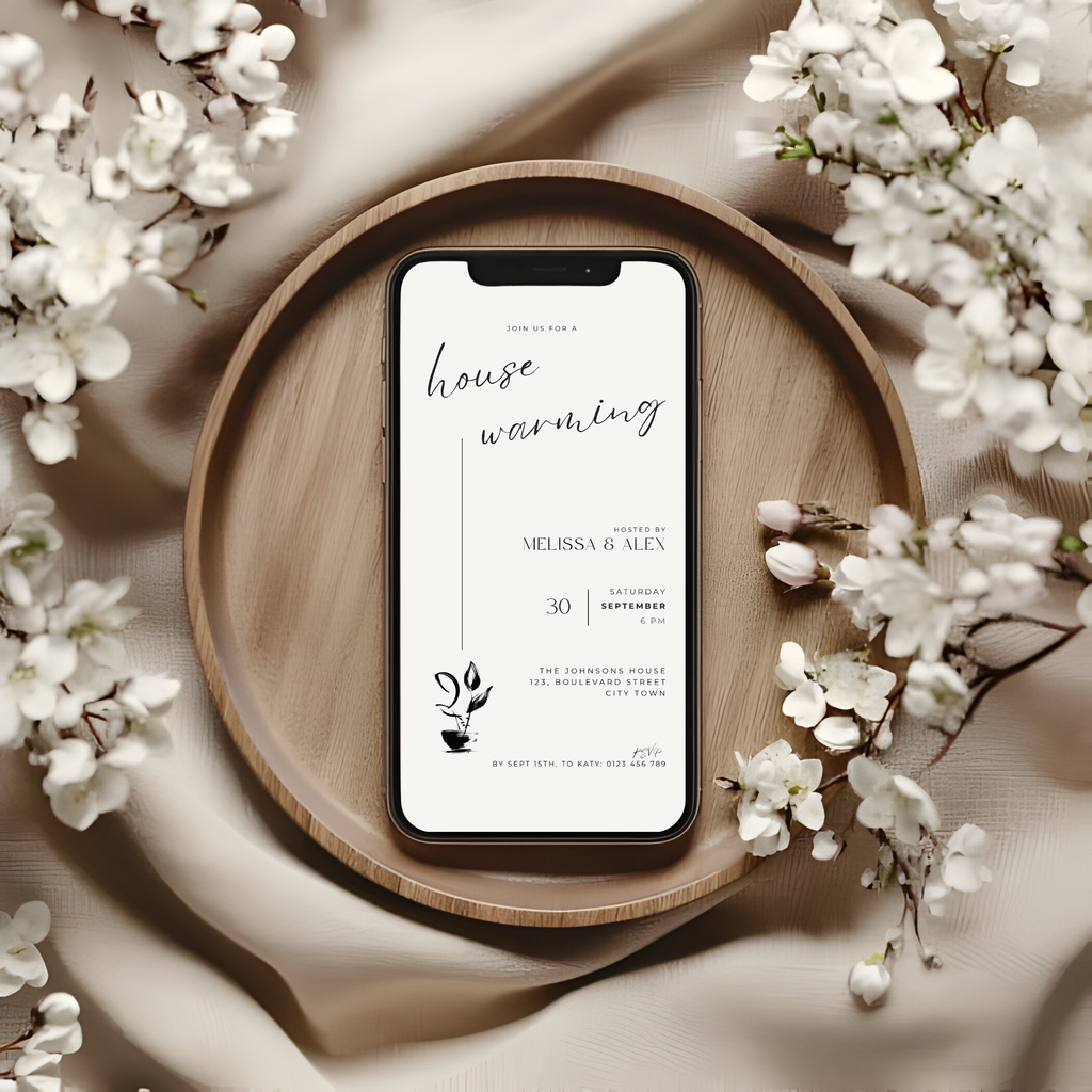 Phone displaying a housewarming invitation on a wooden tray with flowers