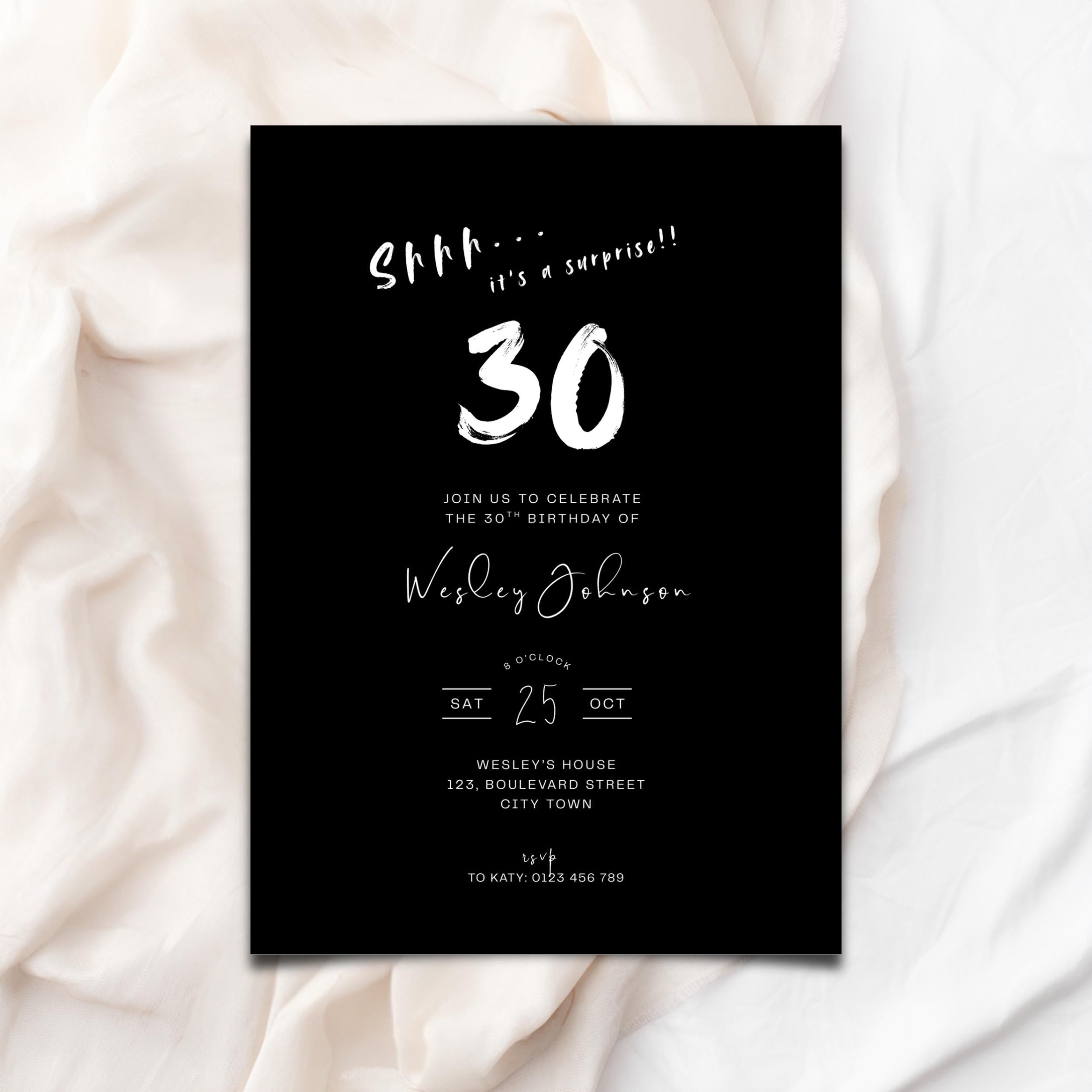 Black 30th birthday invitation card with white text on a white fabric background