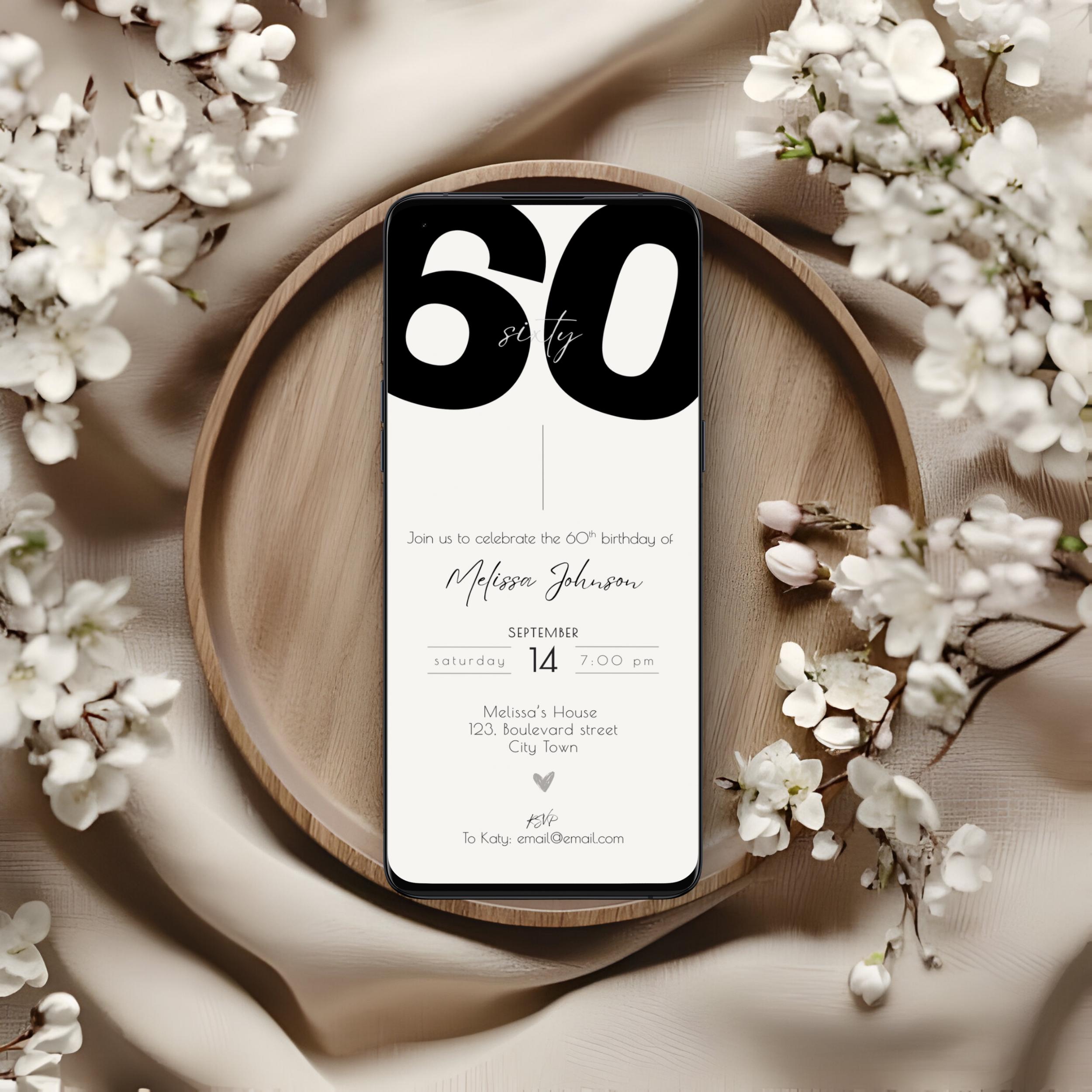 Phone displaying a birthday invitation on a wooden plate with white flowers