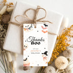 A wrapped gift box tied with twine and adorned with a Halloween-themed 'Thanks Boo' gift tag, styled with dried flowers on a light background.