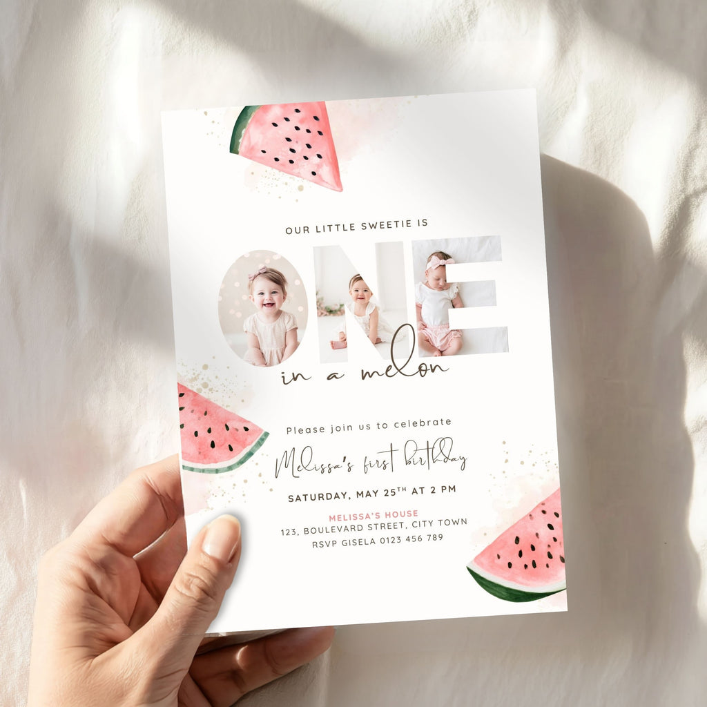 A hand holding a custom watermelon-themed first birthday invitation card against a softly lit, textured white fabric background.