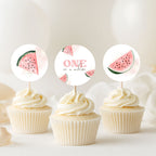Three watercolor-style cupcake toppers with pink watermelon slices and the words 'ONE in a melon' are displayed on top of three frosted cupcakes against a soft, light background.
