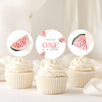 Three watercolor watermelon cupcake toppers displayed on top of white-frosted cupcakes against a soft, light beige background.